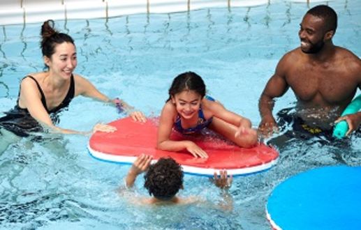 An image of a family in a swimming pool with their child on a swimming float