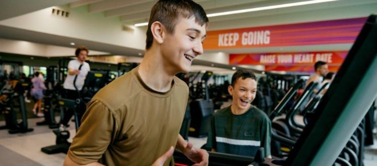 An image of a teenager on a treadmill, laughing with his friend