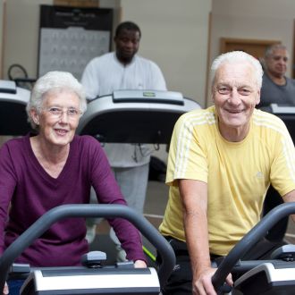 A senior man and lady on a incline bike working out in the gym at Hatfield Swim Centre