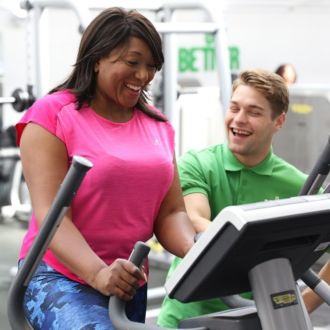 Fitness instructor helping a member with a cardio machine.