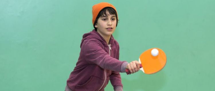 junior with orange hat playing table tennis