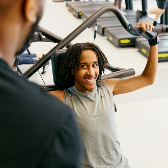 A teenage boy working out with an instructor in the gym