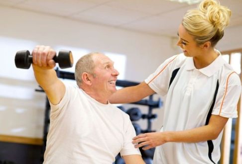Instructor assisting male with correct technique for using weights