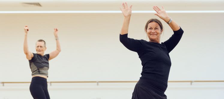 image shows two ladies with their arms raised in a dance position they have smiles on their faces