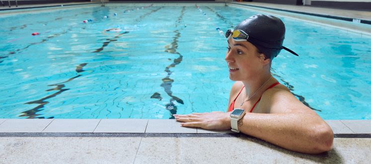 image shows a lady at the edge of the pool smiling