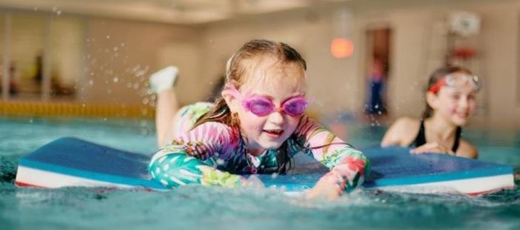 Child using a Pool Mat, wearing goggles and a swimming costume