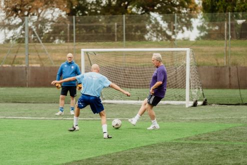 man kicking football on pitch