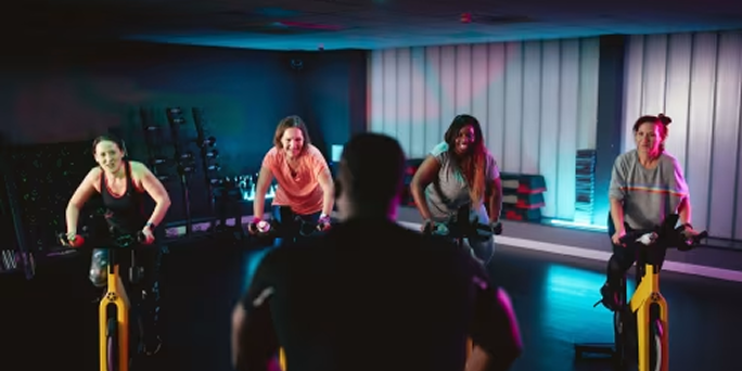 Women working out in a women-only group cycle class  Women working out in a women-only group cycle class