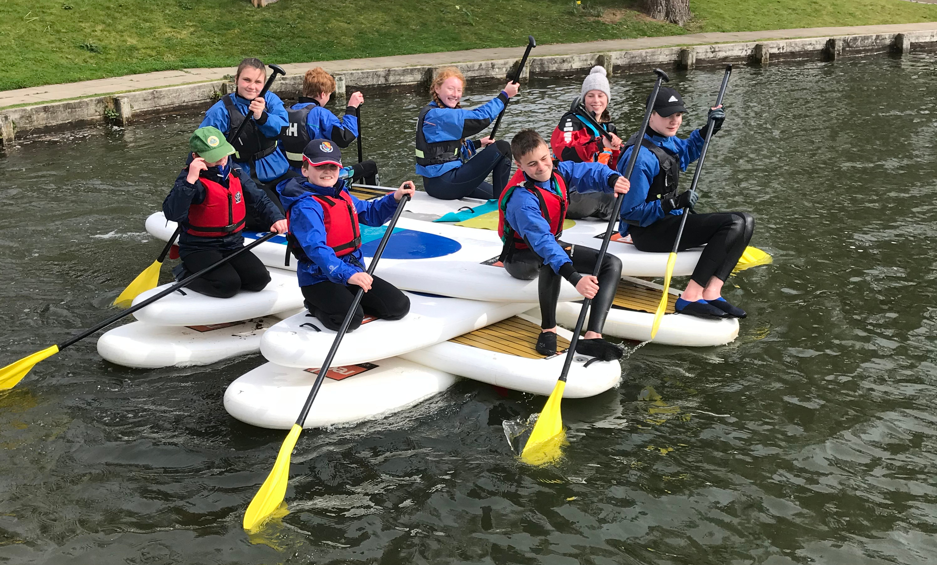 group of happy children standing on a raft made of paddleboards group of happy children standing on a raft made of paddleboards
