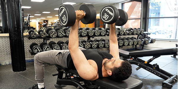 A man working out in the Free Weights Area at Sugden gym using dumbells and bench A man working out in the Free Weights Area at Sugden gym using dumbells and bench
