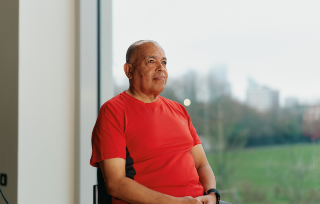 Man wearing a red shirt sitting down in a studio