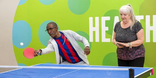 image shows a man and woman playing table tennis.
