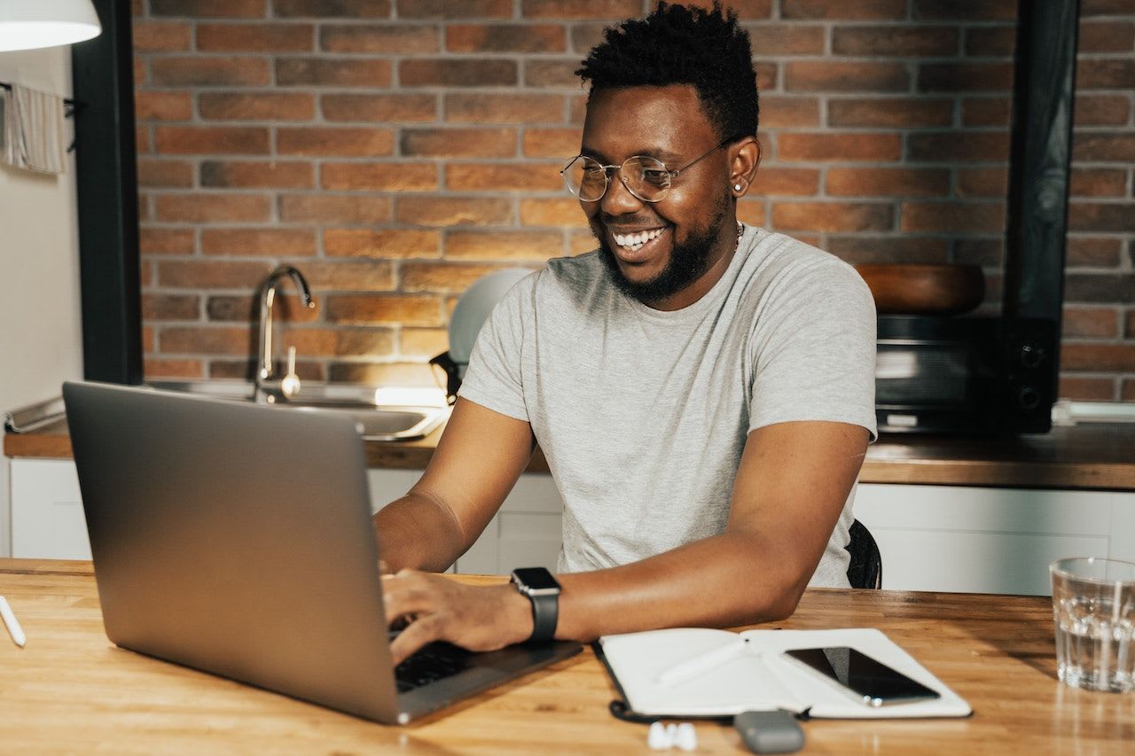 An Australian business owner working at his laptop smiling because he knows how to start a business in Australia