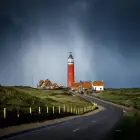 A Winding Road Leading to a Red and White Lighthouse