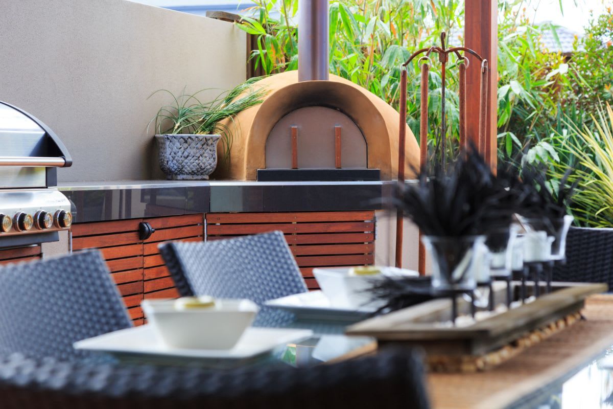 Fertiger Pizzaofen auf einer Terrasse mit Außenküche und Sitzbereich.