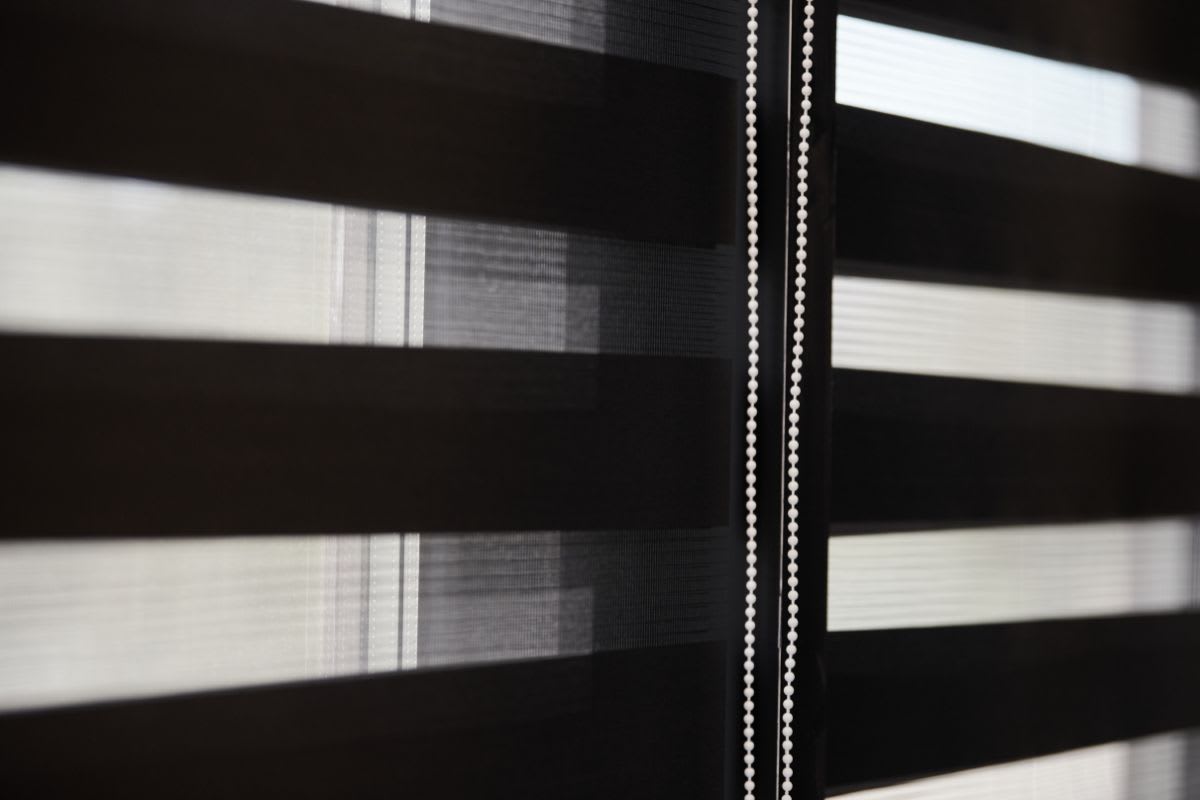 Stoffjalousien an einem Fenster, die teilweise Licht durchlassen und gleichzeitig die Privatsphäre wahren.