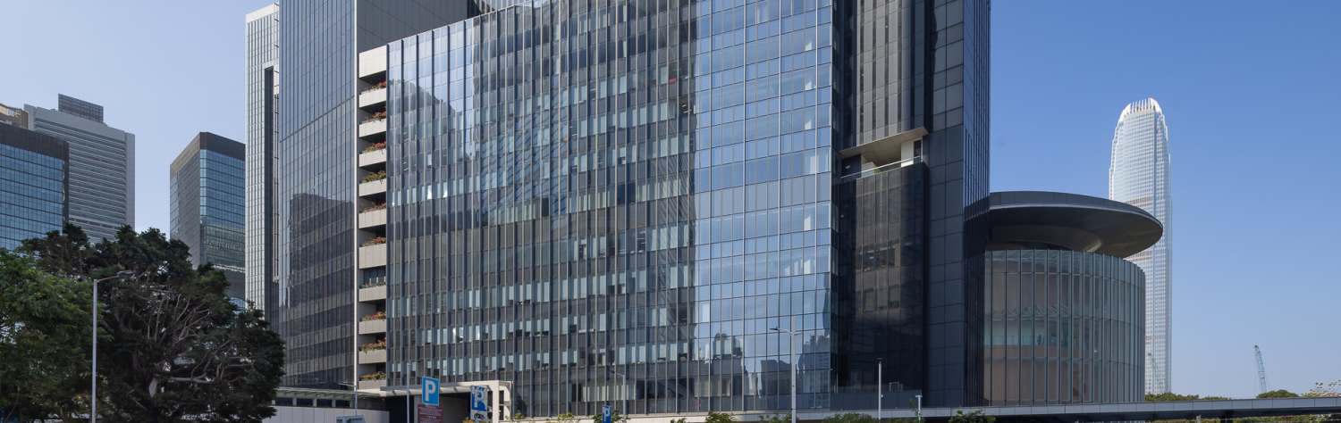 Modern glass skyscraper with a geometric design under a clear blue sky.