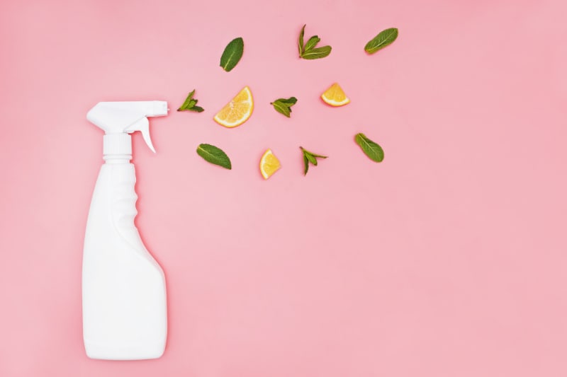 white spray bottle on pink background with lemons and mint
