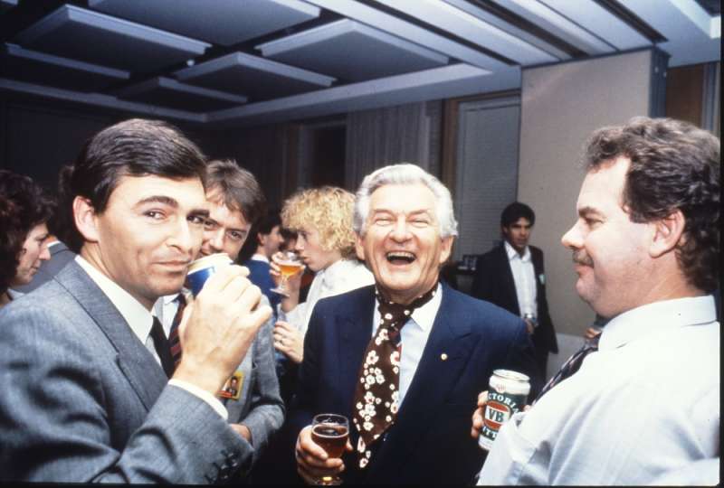 MP John Brumby (left) and Prime Minister Bob Hawke (centre) join colleagues in the Senate Committee Room for a beer and a laugh. Photographer – Robert MacFarlane, Department of the House of Representatives, MoAD Collection.
