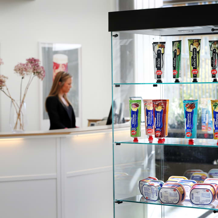 I bakgrunden står receptionist vid receptiondisk, i förgrunden ett utbud av Kavlis produkter i en glasmonter