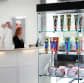 I bakgrunden står receptionist vid receptiondisk, i förgrunden ett utbud av Kavlis produkter i en glasmonter