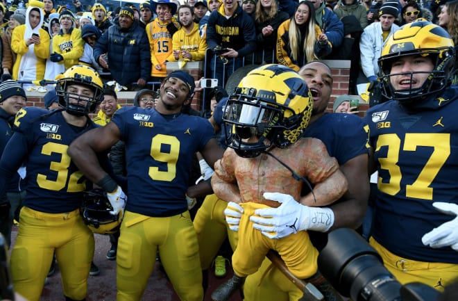 The Michigan Wolverines football team poses with the Paul Bunyan Trophy