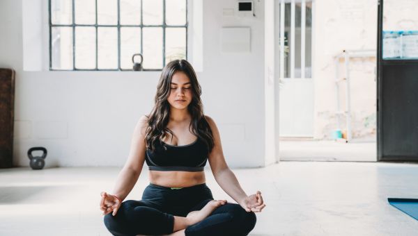 young woman outside practicing easy pose for yoga