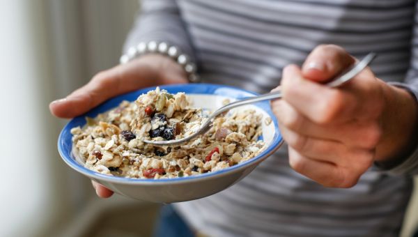 woman holding a bowl of oatmeal muesli and a spoon