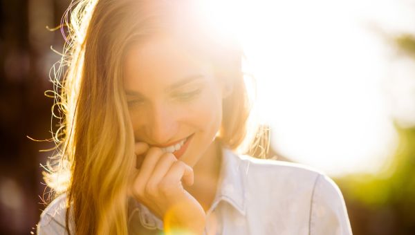 shy woman with sun behind her