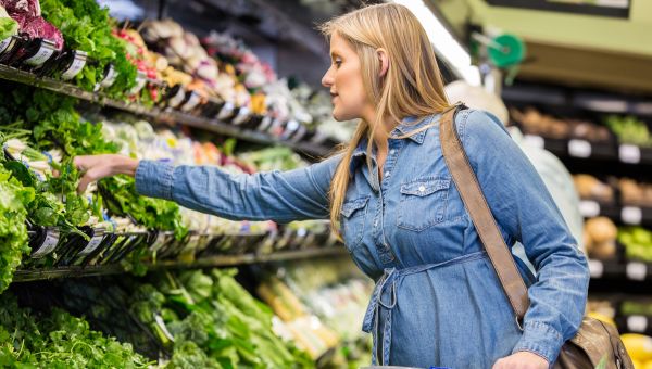 pregnant person shopping in the produce section of a super market