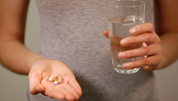woman taking allergy pills with a glass of water