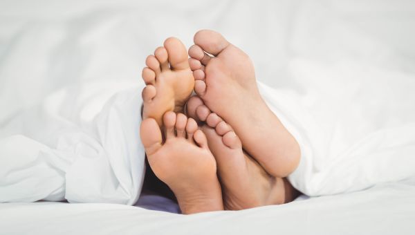 Two pairs of bare feet sticking out from under a sheet