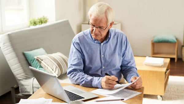 elderly man, computer, laptop, planning, pen and paper, home office