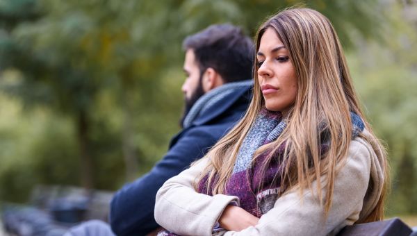 pensive person sitting next to another person, outside, scarf