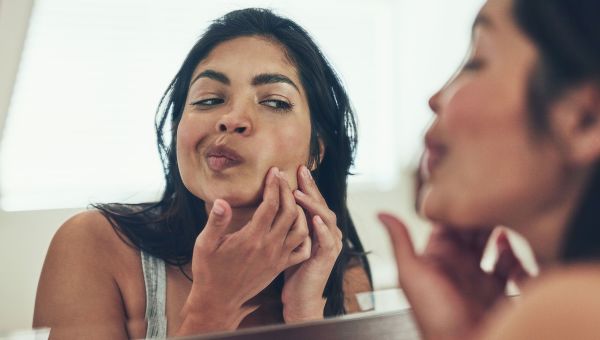 woman pops pimple on face