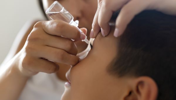 little boy with eye drops for pink eye