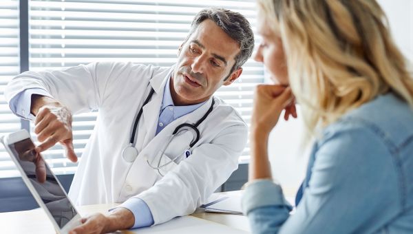 doctor showing woman test results on laptop