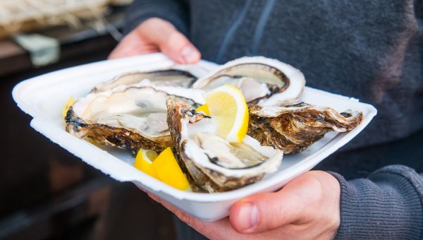 Oysters with lemons in a styrofoam tray.