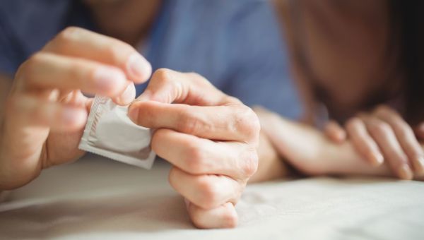 Man opening the wrapper to a condom.