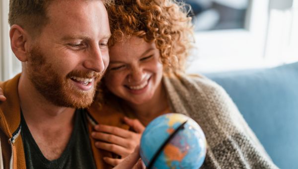 young white smiling couple look at miniature globe
