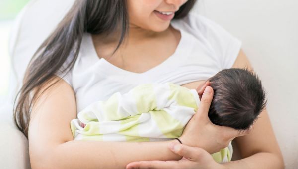 Parent smiling while breastfeeding their newborn.