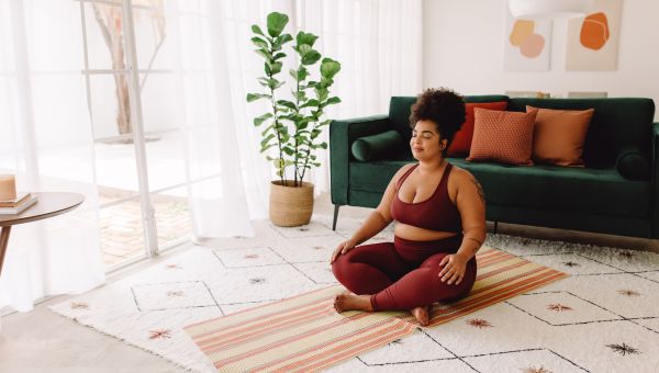 a young overweight Black woman meditates in a nice living room 