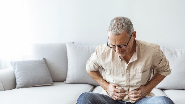 mature man clutching stomach in pain