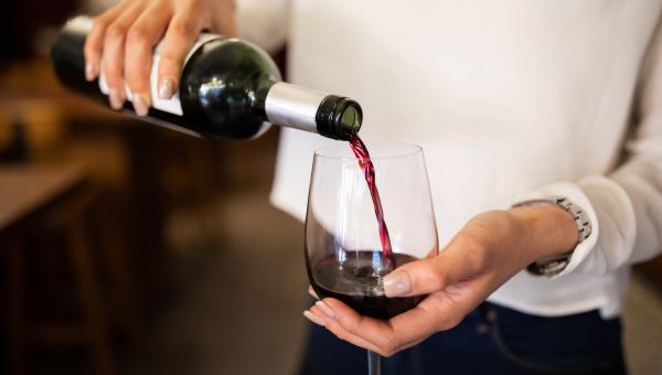 closeup of a woman's hands pouring a glass of red wine