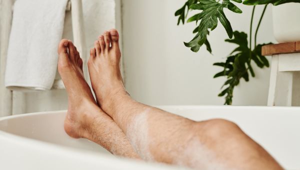 a man's bare feet protrude from the end of a bubble bath