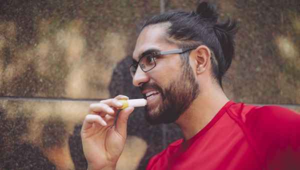 man applying chapstick or lip balm outdoors
