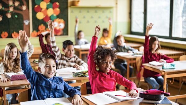 children raising hands in classroom