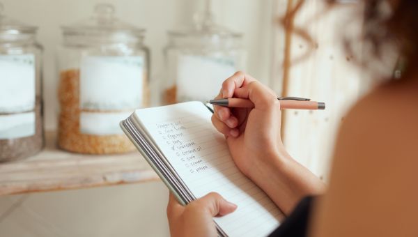 woman's hand writing grocery list