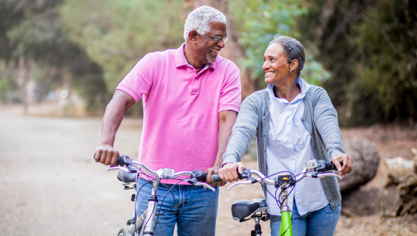 happy senior couple walking their bikes in a park