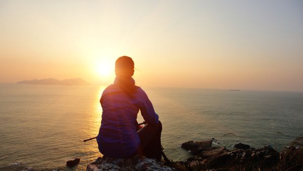 woman sitting in sunlight with backpack